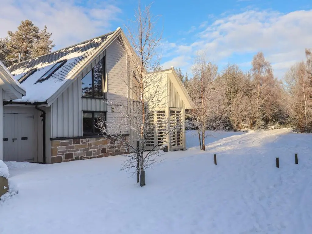 a house in the snow with a snow covered yard at Mountain Hare Apartment in Kingussie
