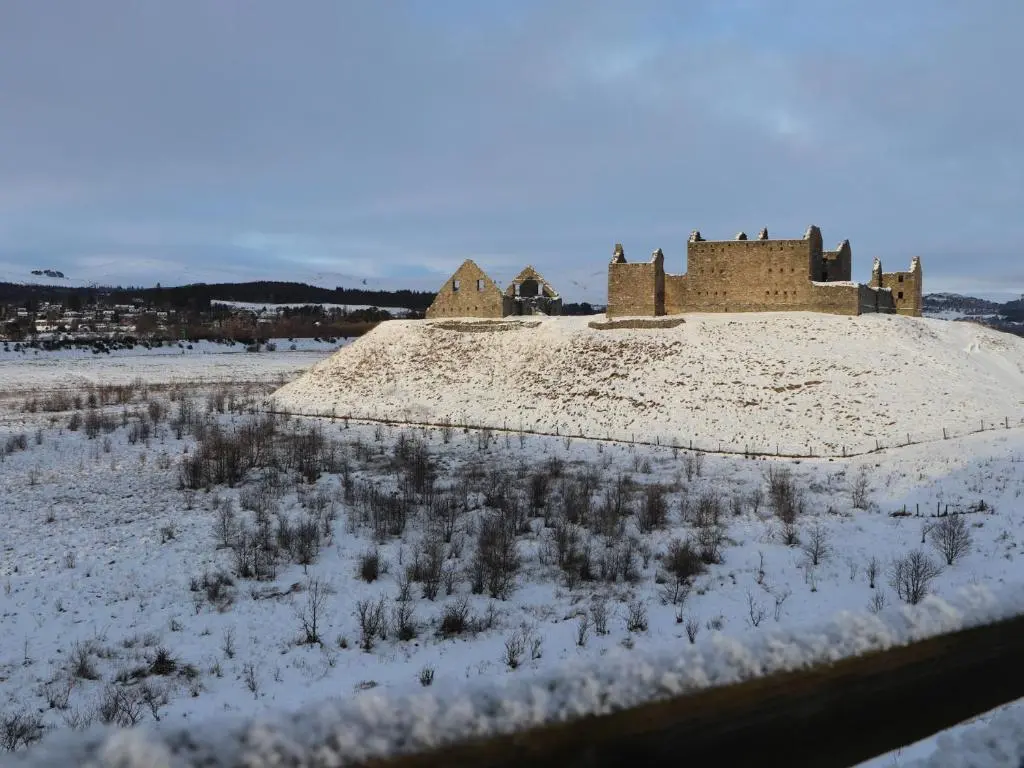 an old castle in the middle of a snow covered field at Mountain Hare Apartment in Kingussie