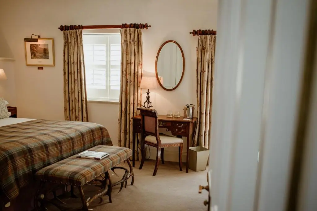 a bedroom with a bed and a desk and a mirror at Links House at Royal Dornoch in Dornoch
