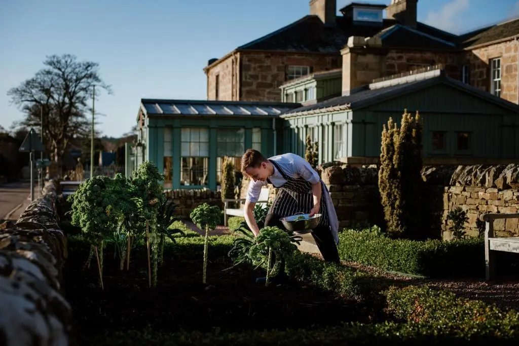 a woman standing in a garden tending to plants at Links House at Royal Dornoch in Dornoch