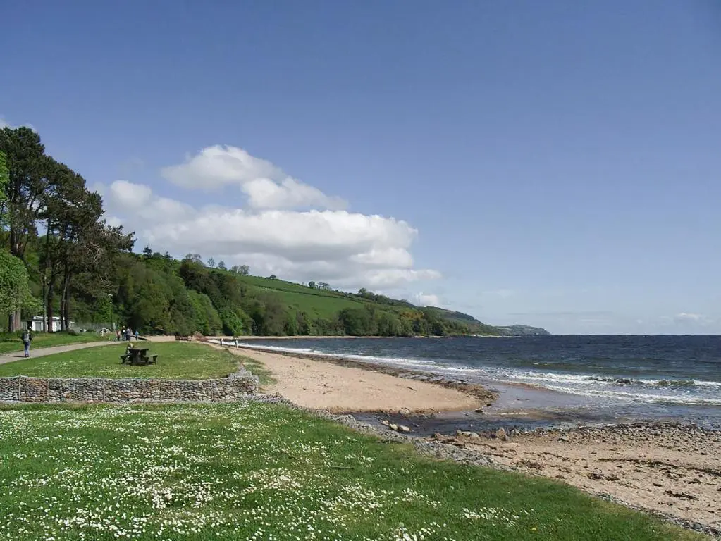 a beach with people sitting on a bench next to the water at Pine Lodge - Uk7049 in Glenurguhart