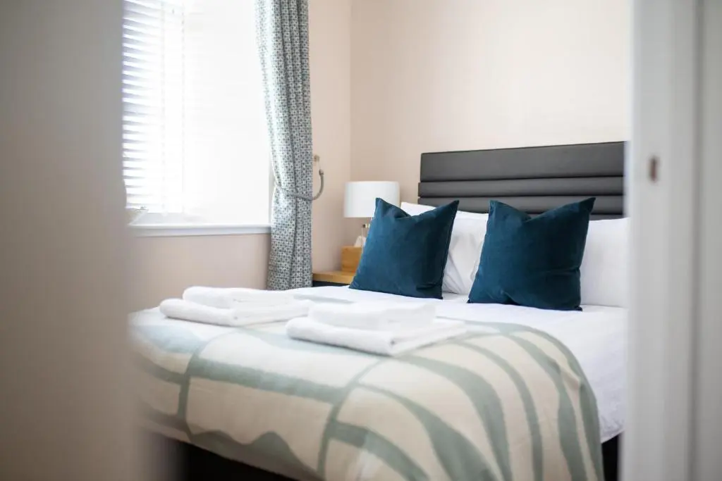 a bedroom with a large bed with blue pillows at Old Edinburgh Court in Inverness