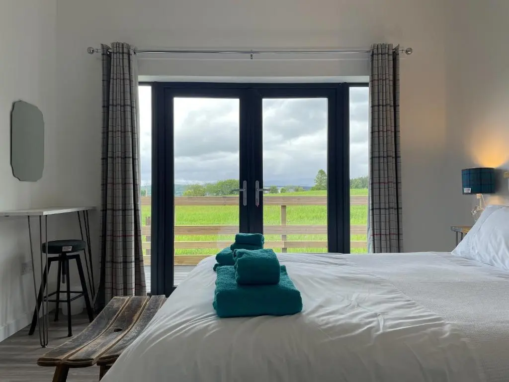 a bedroom with a bed with a view of a field at Willow Lodge in Muir of Ord