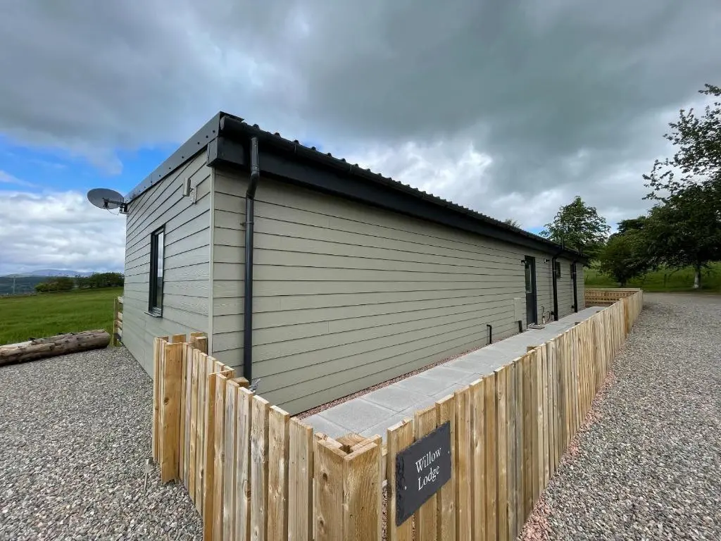 a building with a fence in front of it at Willow Lodge in Muir of Ord