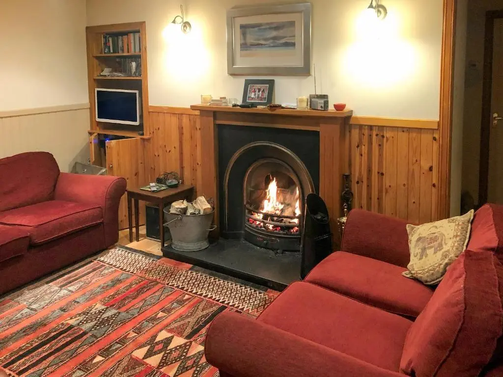 a living room with a fireplace with two red couches at Crofts in Badenyon