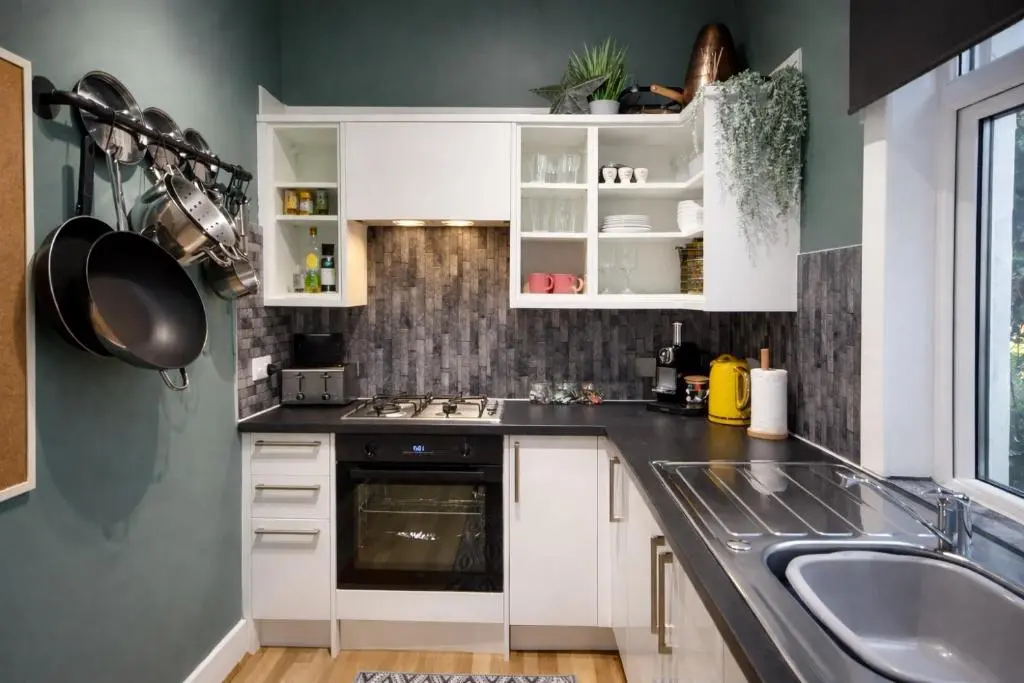a kitchen with white cabinets and a sink at Lamont Cottage in Inverness