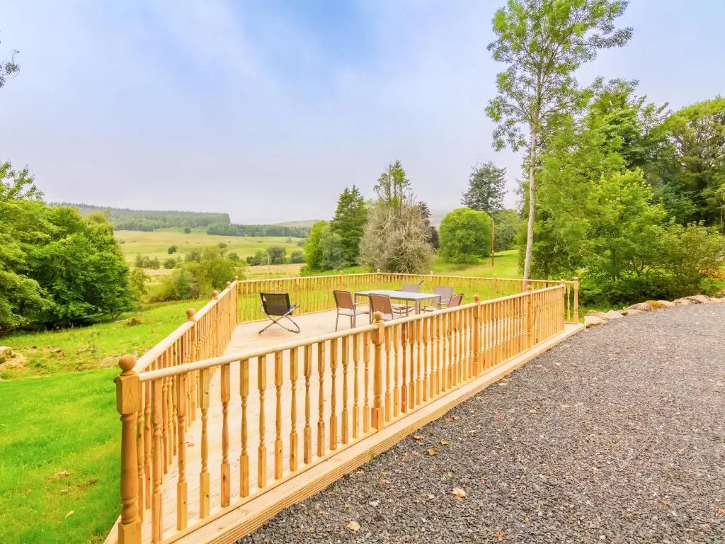 a wooden deck with a table and chairs on it at Dalnaglar Cottage - Uk30260 in Cray