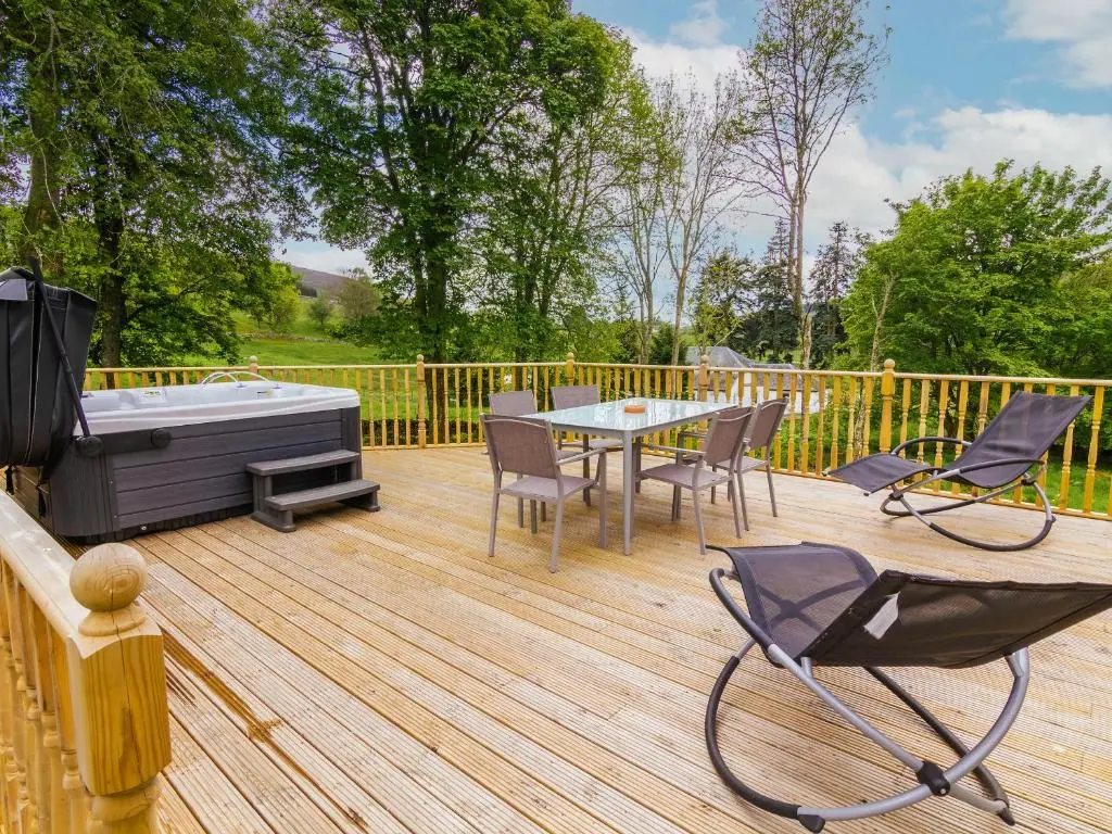 a deck with a hot tub and a table and chairs at Dalnaglar Cottage - Uk30260 in Cray