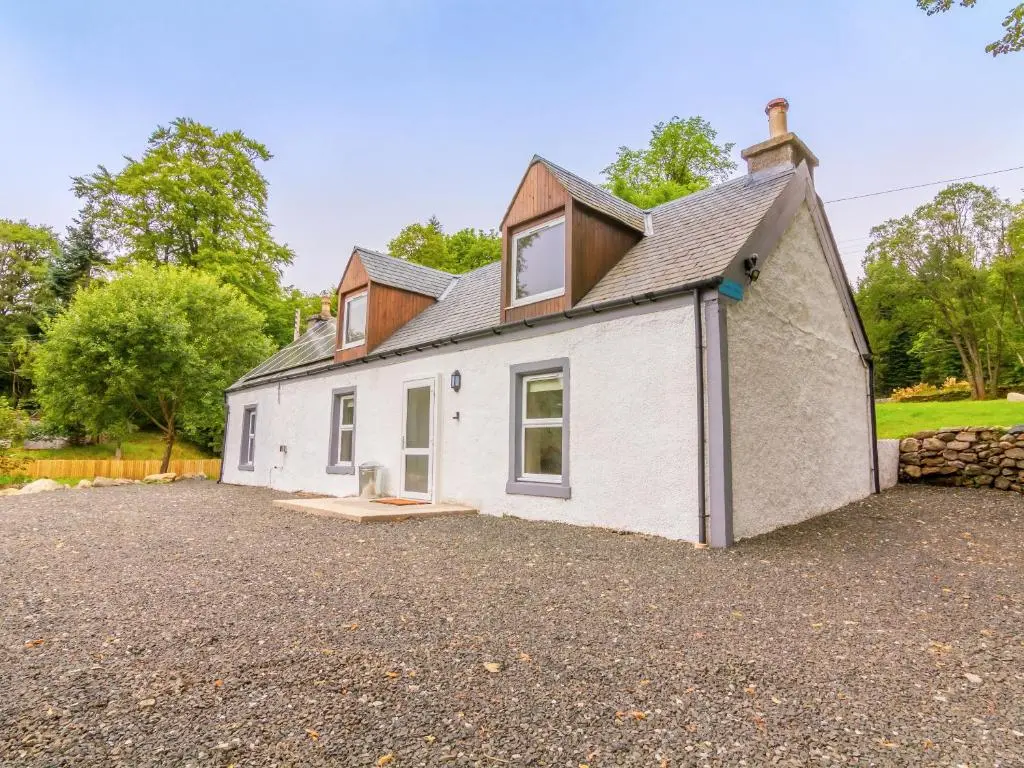 a white house with a roof on a gravel driveway at Dalnaglar Cottage - Uk30260 in Cray