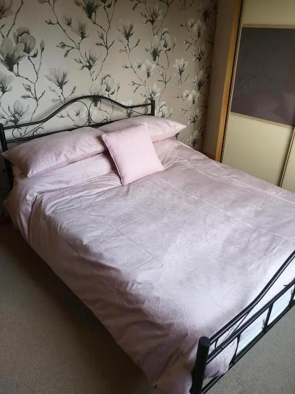 a bedroom with a bed with a pink pillow at Highland Home From Home in Inverness