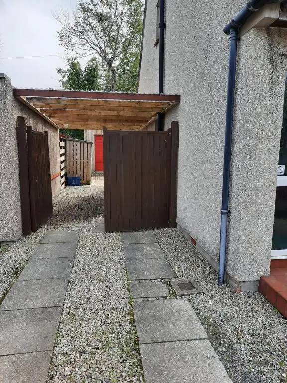 a garage with a wooden gate in front of a building at Highland Home From Home in Inverness