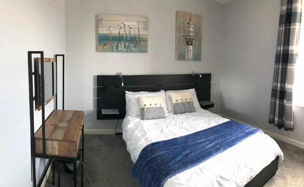 a bedroom with a large bed with a blue blanket at The Steamboat - A Flat with Amazing Harbour Views in Wick