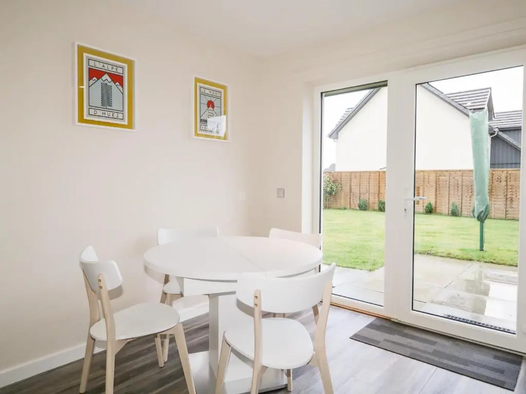 a white dining room with a white table and chairs at Skoglendi in Boat of Garten
