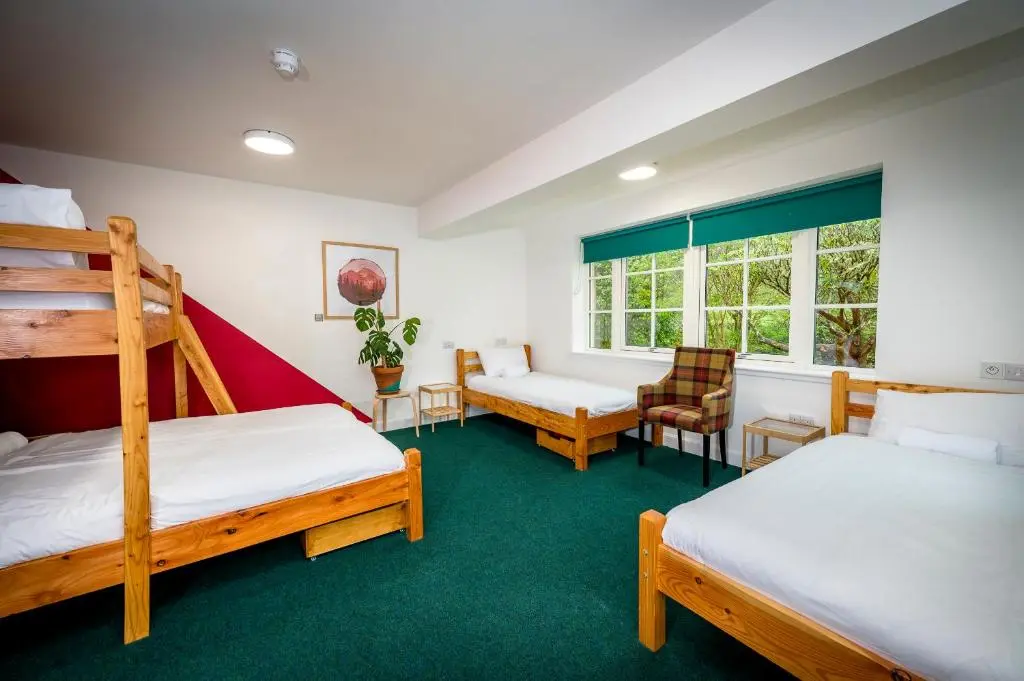 a room with two bunk beds and a chair at Loch Ness Bunk Inn in Drumnadrochit
