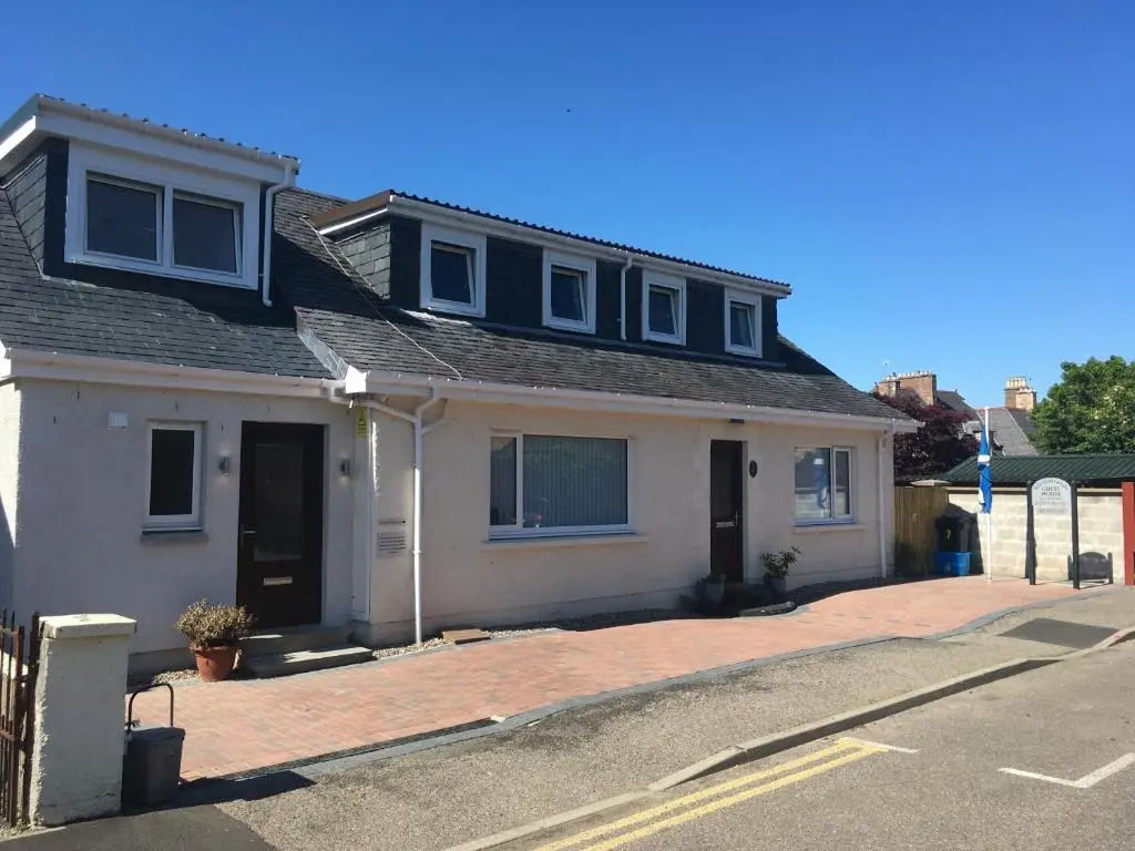 a white house with a black roof on a street at Silverstrands in Inverness
