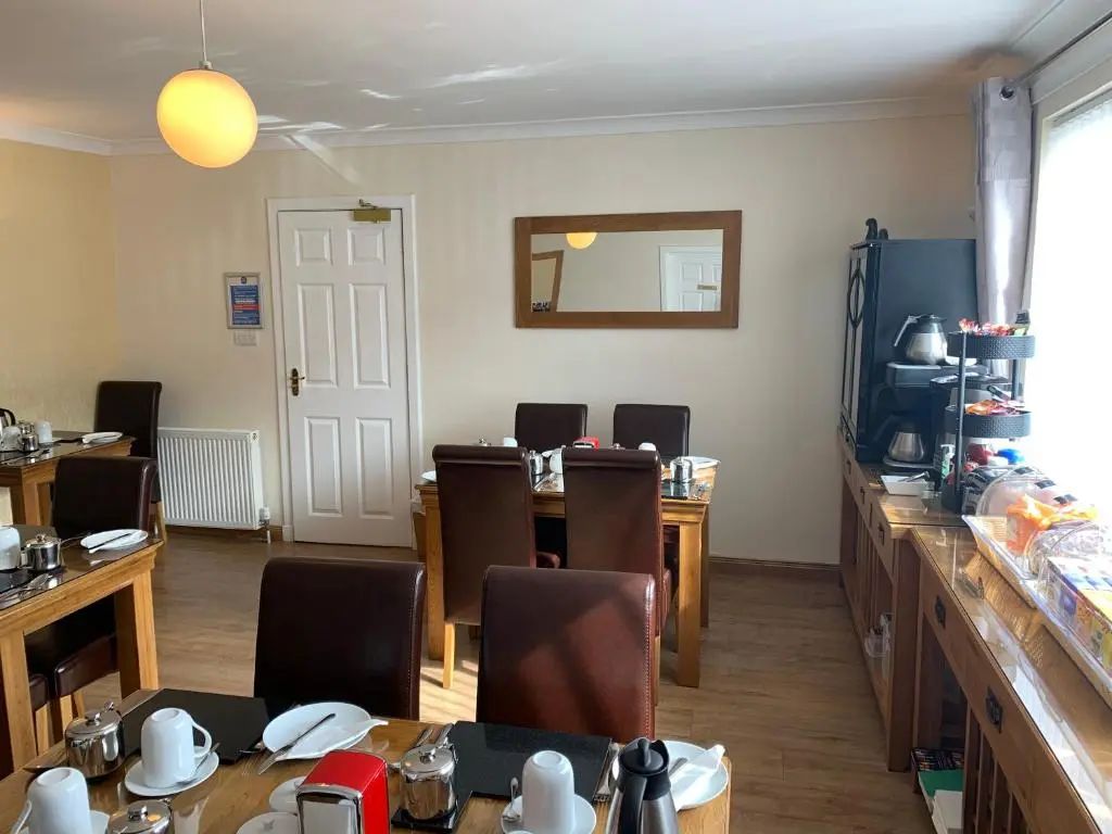a dining room with tables and chairs and a television at Silverstrands in Inverness