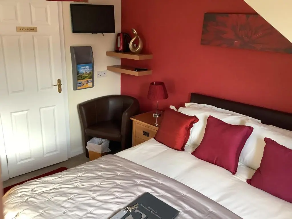 a bedroom with a bed with red walls and a chair at Silverstrands in Inverness