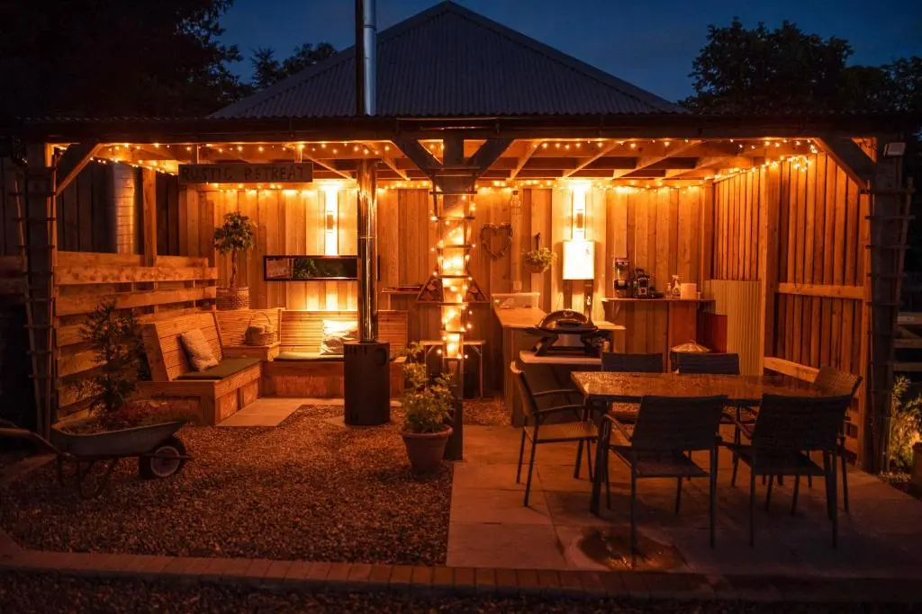 a pergola with lights on a patio at night at Larchwood Lodge in Ellon