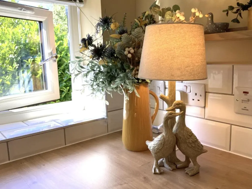 two wooden ducks standing next to a lamp on a kitchen floor at Larchwood Lodge in Ellon