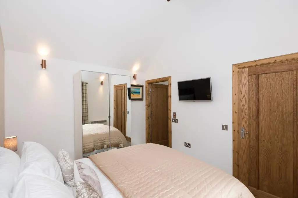a bedroom with a bed and a mirror and a tv at The Milking Sheds, Dufftown in Dufftown