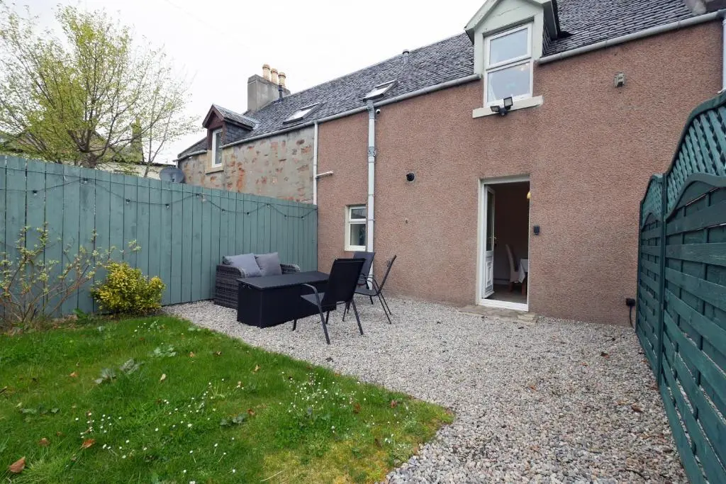 a backyard with a fence and a table and chairs at Ardentorrie Holiday Home in Inverness