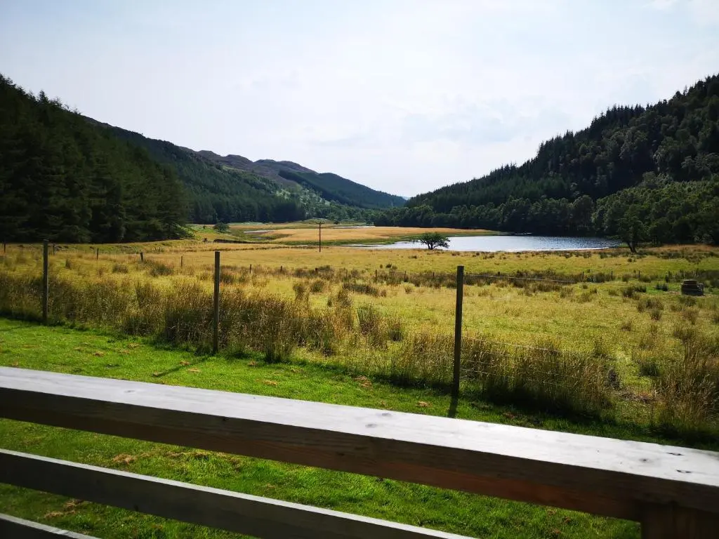 a view of a field with a river and a fence at Craskie Glamping Pods in Inverness