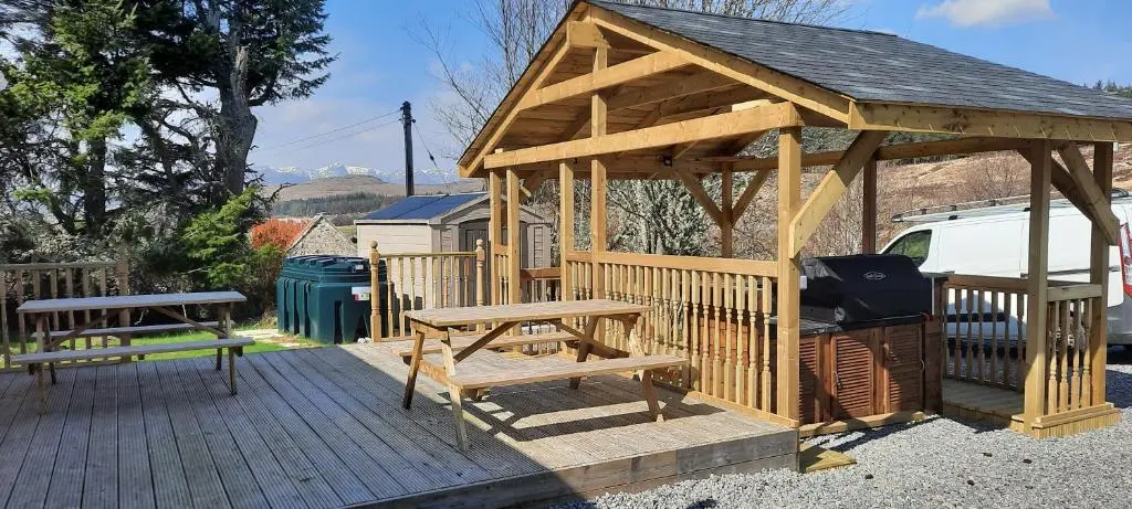 a wooden gazebo with a picnic table and a bench at Balintombuie in Dalchreichart