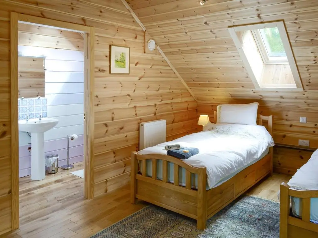a bedroom with a bed in a wooden room at Moonshine Cottage in Culbokie