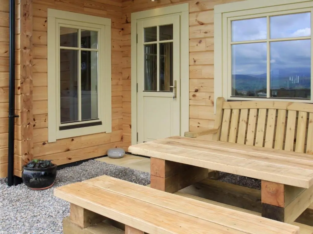 a wooden bench sitting on the porch of a cabin at Moonshine Cottage in Culbokie