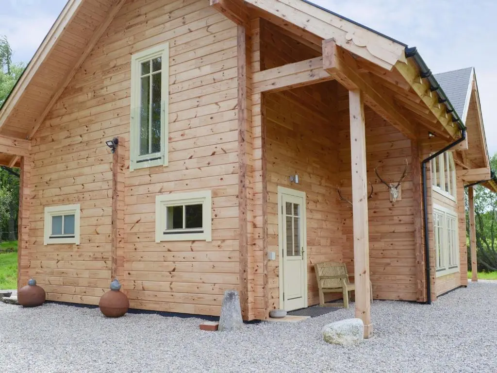 a log cabin with a large open door at Moonshine Cottage in Culbokie