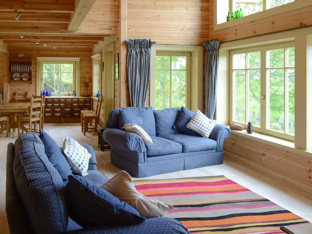 a living room with blue couches and a dining room at Moonshine Cottage in Culbokie