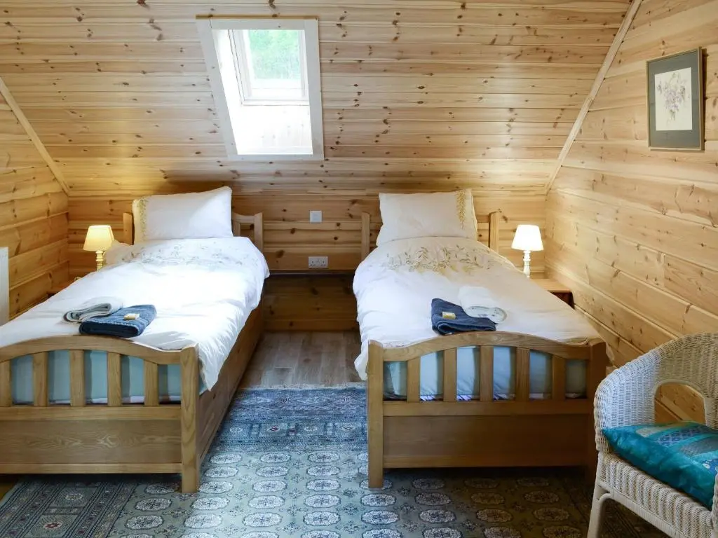 a bedroom with two beds in a log cabin at Moonshine Cottage in Culbokie