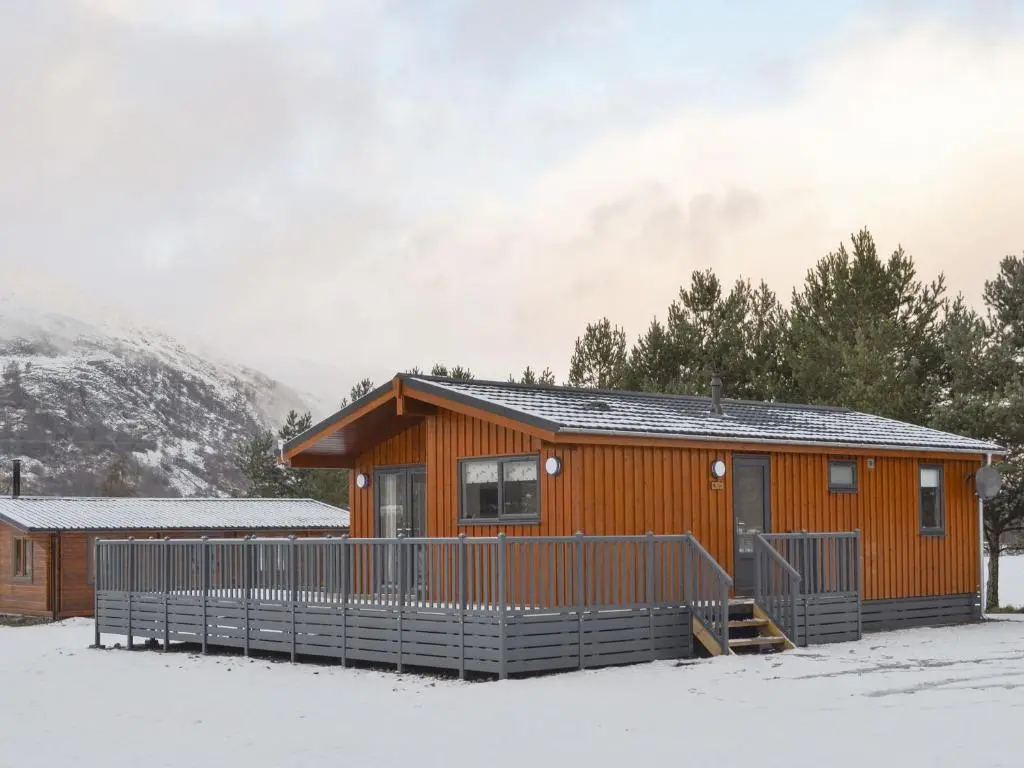a log cabin in the snow with a mountain at The Den in Etteridge