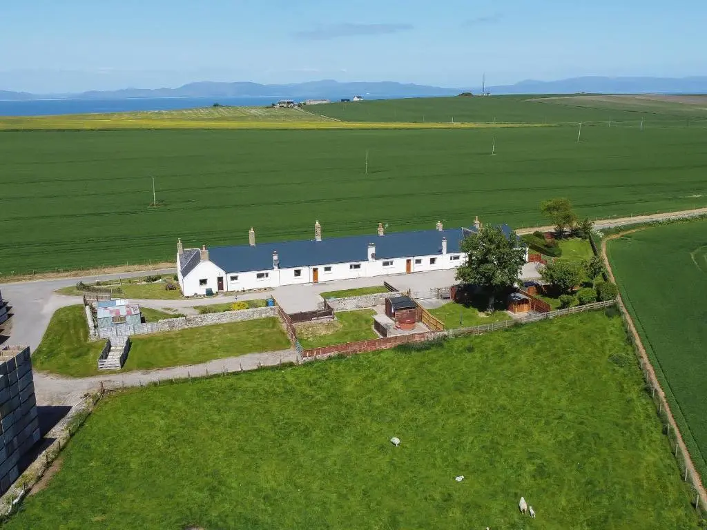 an aerial view of a large white building with a grass field at Grieve's Cottage in Portmahomack