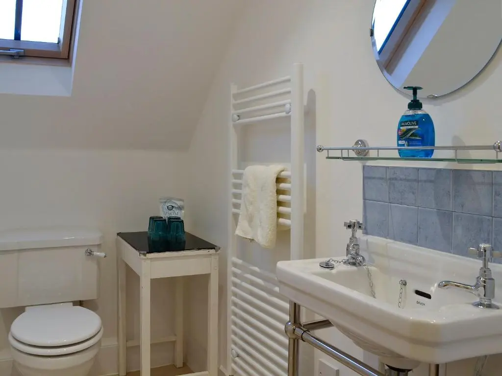 a bathroom with a sink and a toilet and a mirror at Dairy Cottage in Whitehouse