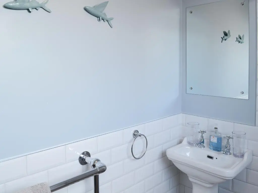 a white bathroom with a sink and a mirror at Sea Thistle Cottage in Nairn