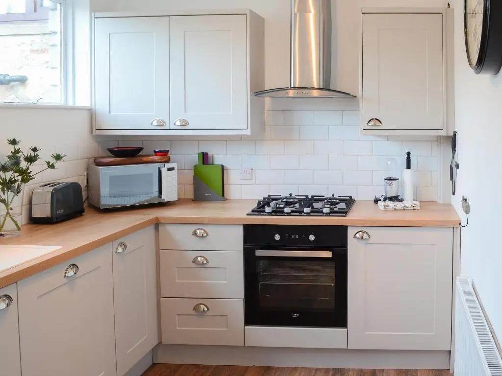 a kitchen with white cabinets and a stove top oven at Sea Thistle Cottage in Nairn