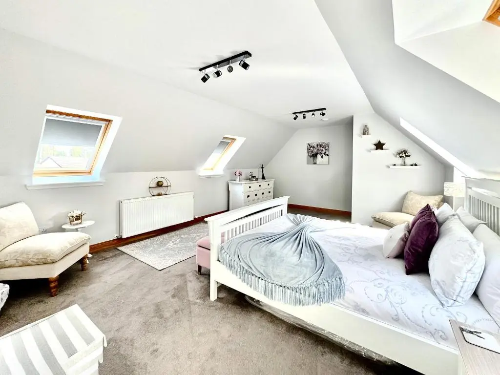 a white bedroom with a bed and a chair at Rose Cottage in Dingwall