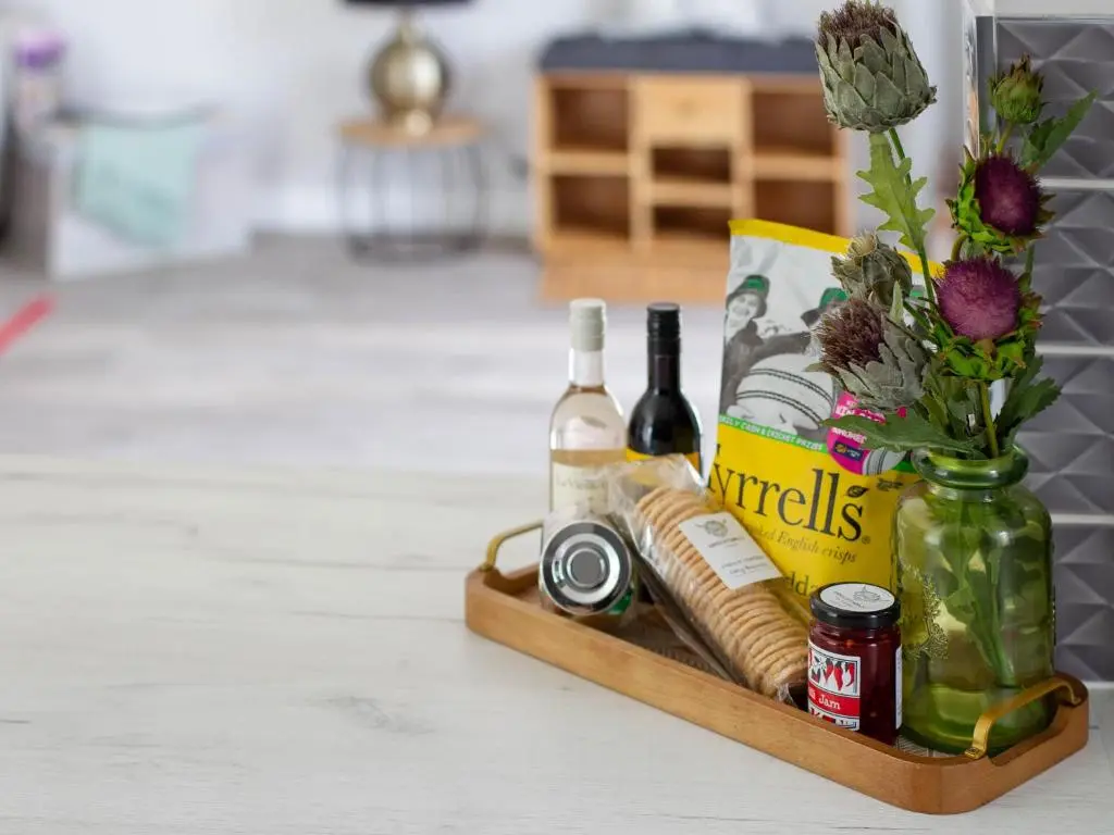 a wooden tray with bottles of wine and a vase of flowers at Rose Cottage in Dingwall