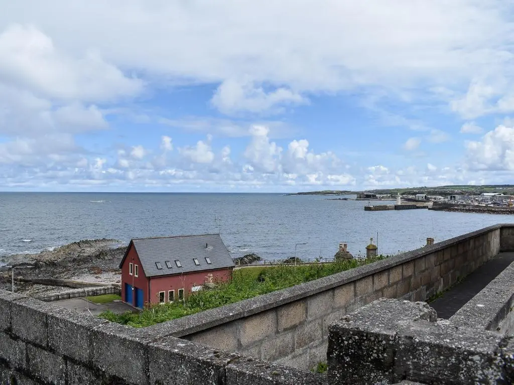 a red house on the shore of a body of water at Sea Breeze Cottage in Buckie