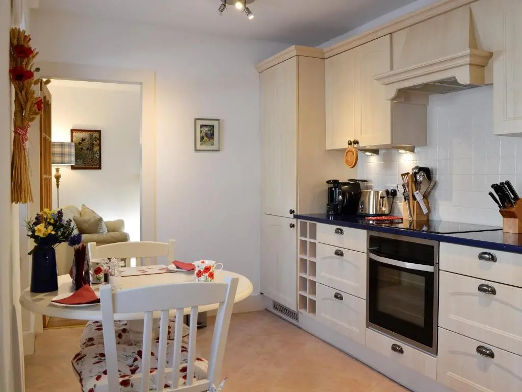 a kitchen with white cabinets and a table and chairs at Craigclunie in Ballater