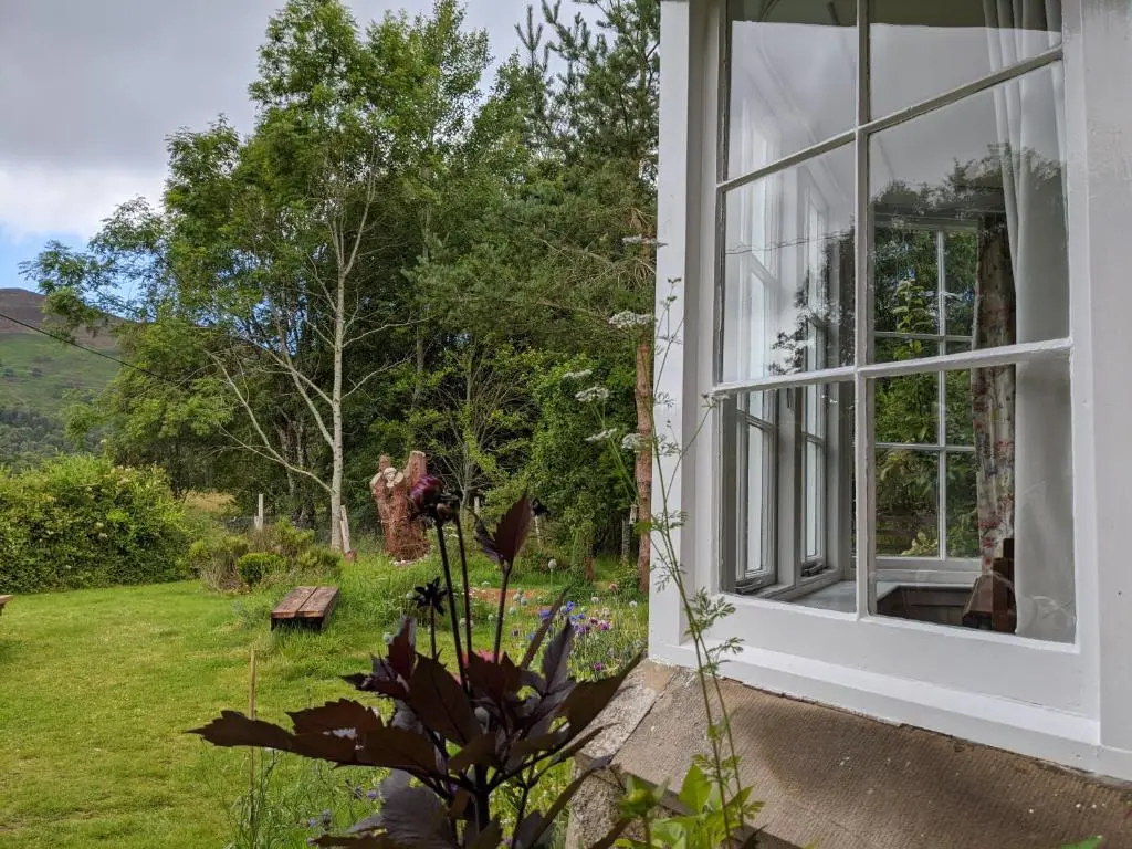 a window of a house with a view of a garden at Thistle Cottage, CrannachCottages in Garve