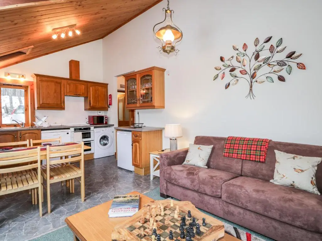 a living room with a couch and a table at Torbreck Chalet in Kingussie