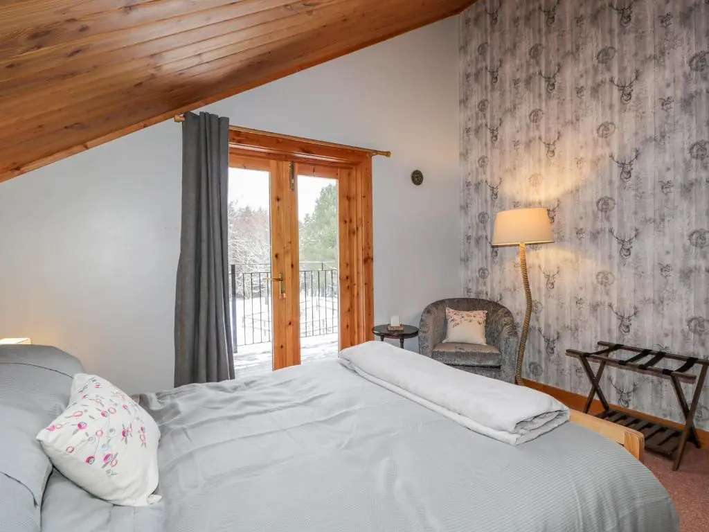 a bedroom with a white bed and a window at Torbreck Chalet in Kingussie