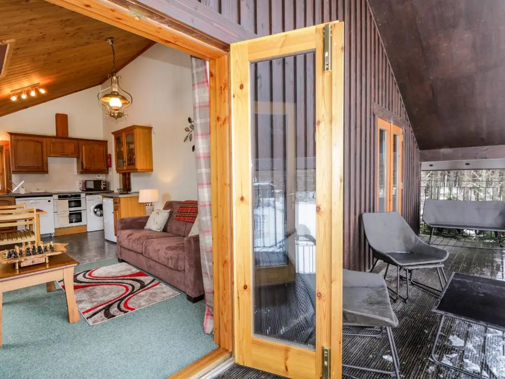 a living room and kitchen with a sliding glass door at Torbreck Chalet in Kingussie