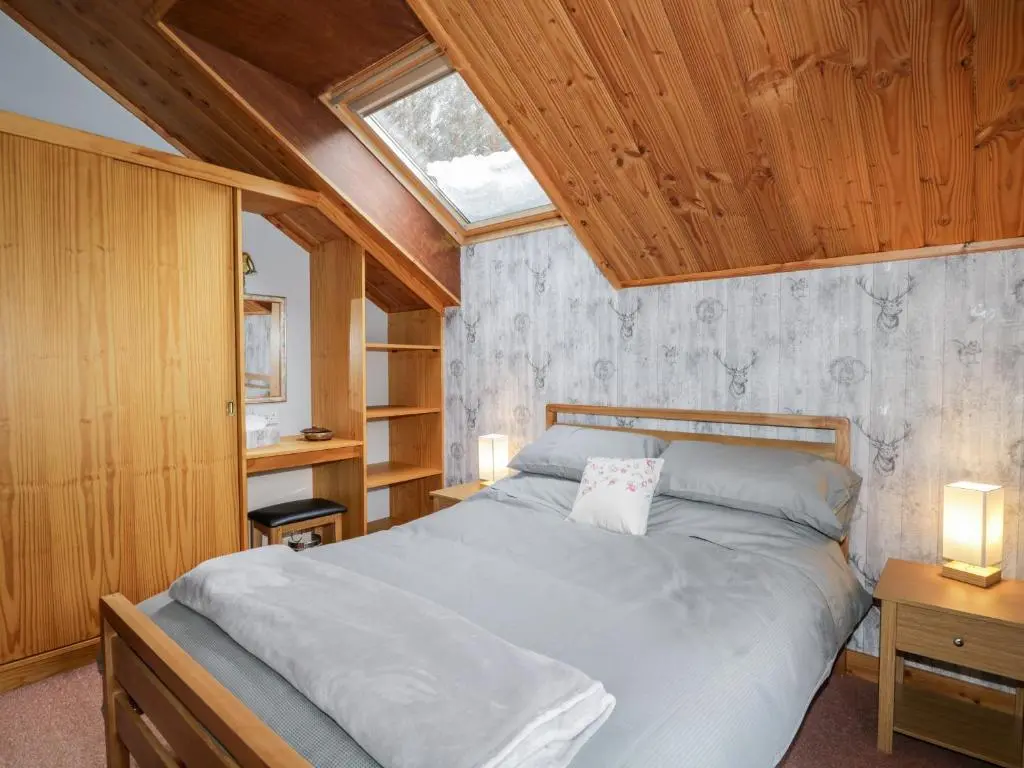 a bedroom with a bed and a wooden ceiling at Torbreck Chalet in Kingussie
