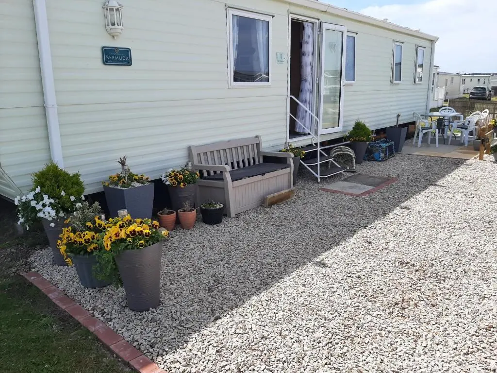 a patio with a bench and potted plants next to a house at Taid's Retreat Silversands Cove beach lossiemouth in Lossiemouth