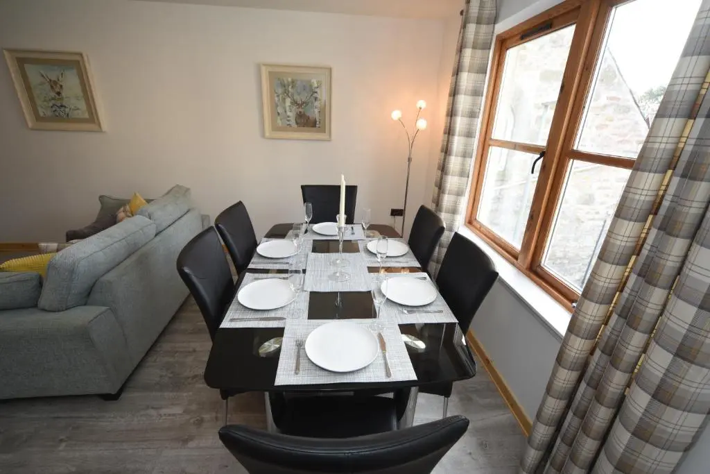 a dining room with a table and a couch at Silver Key Apartment 2 in Inverness