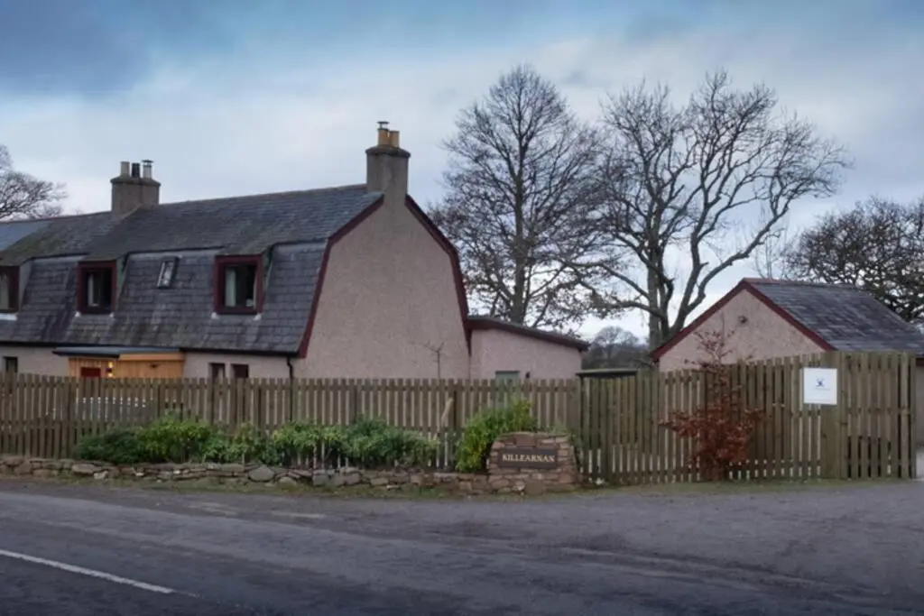 a house with a wooden fence next to a house at Drumossie Bothy in Inverness