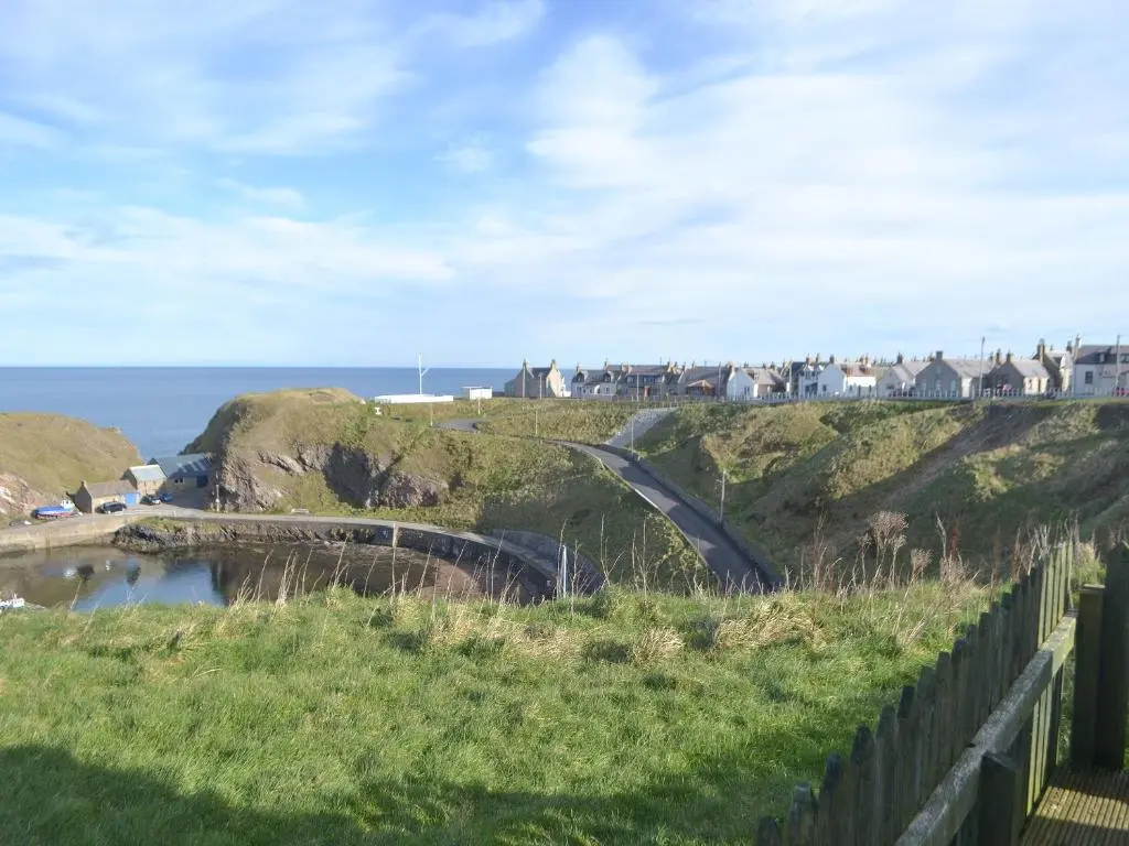 a road on a hill next to the ocean at Dolphin View - Uk30689 in Portknockie